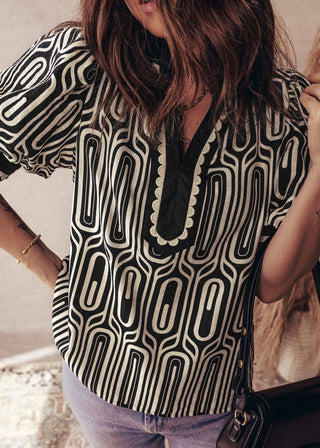 Person wearing a black and white patterned blouse with a blurred background