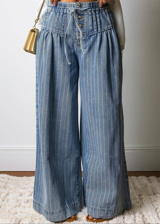 Person wearing blue striped wide-leg jeans with a neutral background