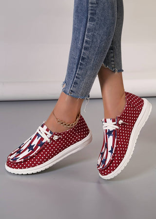 Casual canvas shoes with a patriotic stars, stripes, and polka dot design, shown worn with jeans and a gold anklet.