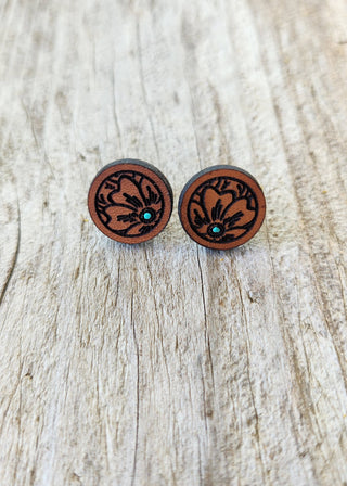 Wooden earrings with intricate designs on a wooden surface