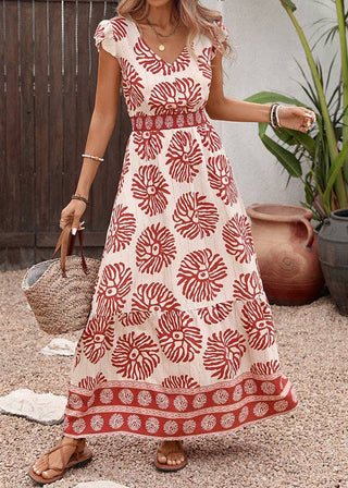 Woman wearing a white dress with red floral pattern outdoors.