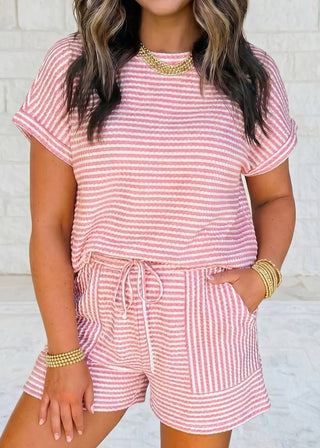 Woman wearing a pink and white striped outfit with a matching top and shorts.