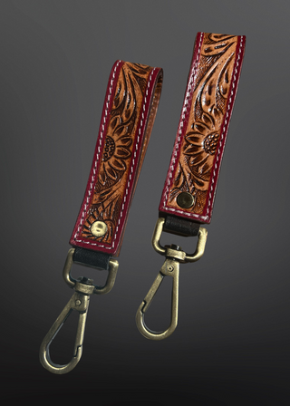 Two leather keychains with floral patterns on a dark gray background