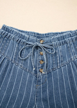 Close-up of blue denim shorts with button details on a beige background