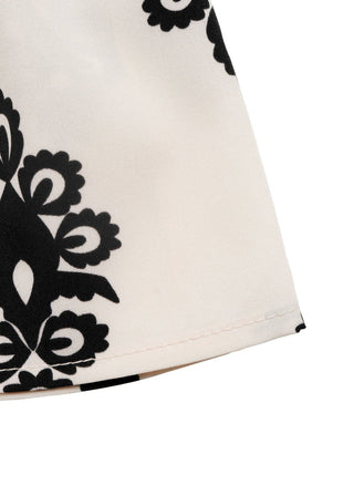 Close-up of a white garment with black floral patterns on a white background