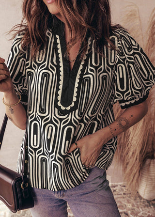 Person wearing a black and white patterned shirt with a blurred background