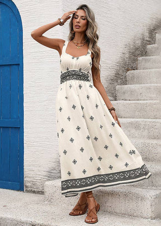 Woman in a white dress with black patterns standing on stone steps next to a blue door.