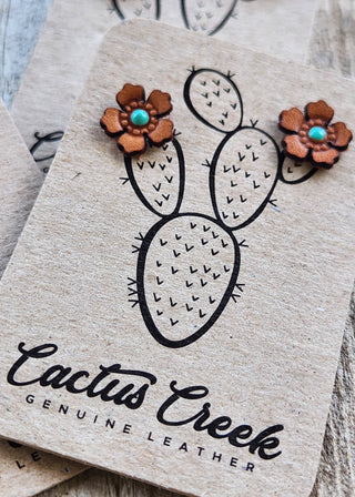 Cactus-shaped leather earrings on a branded card with 'Cactus Creek' branding.