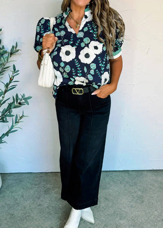 Woman wearing a floral blouse and black pants with a white background